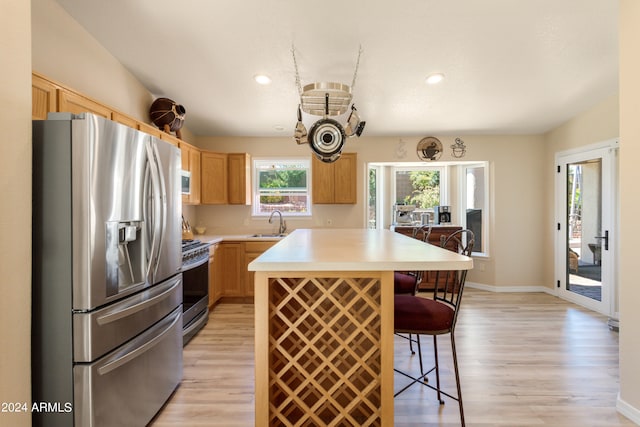 kitchen with light hardwood / wood-style flooring, stainless steel appliances, a kitchen breakfast bar, and a kitchen island