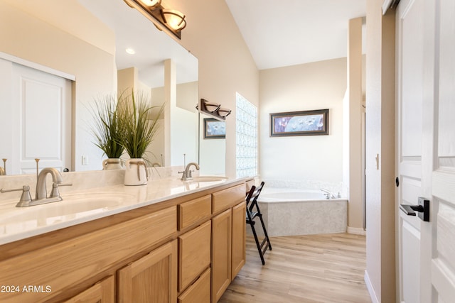 bathroom with lofted ceiling, vanity, hardwood / wood-style floors, and a tub