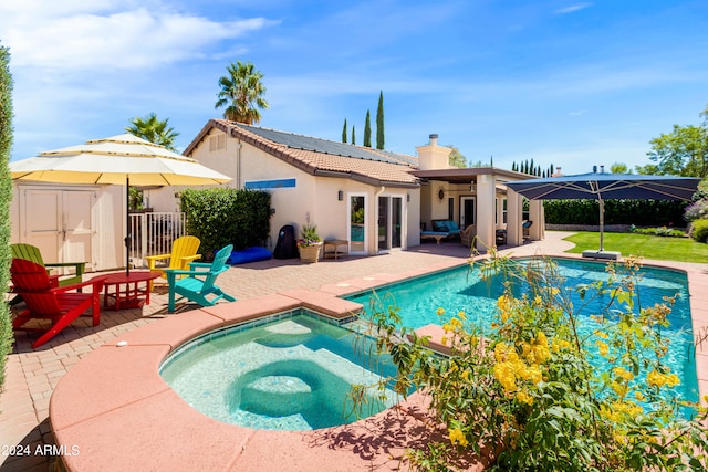 view of swimming pool featuring a patio, a storage shed, and an in ground hot tub