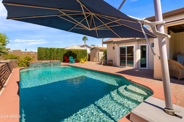 view of swimming pool featuring a patio, a storage shed, and an in ground hot tub