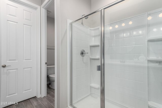 bathroom featuring wood finish floors, a stall shower, and toilet