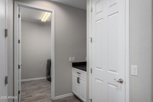 bathroom with wood finish floors, washer / clothes dryer, vanity, and baseboards