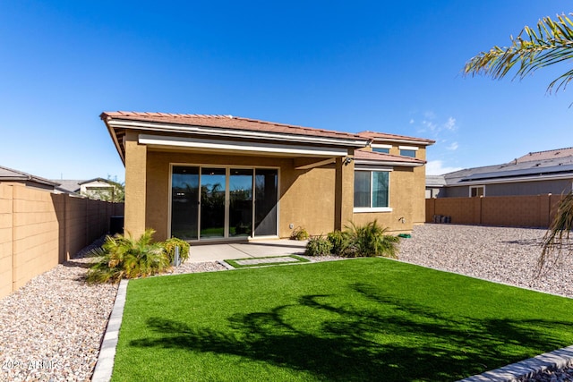 rear view of property with a yard, a fenced backyard, and stucco siding