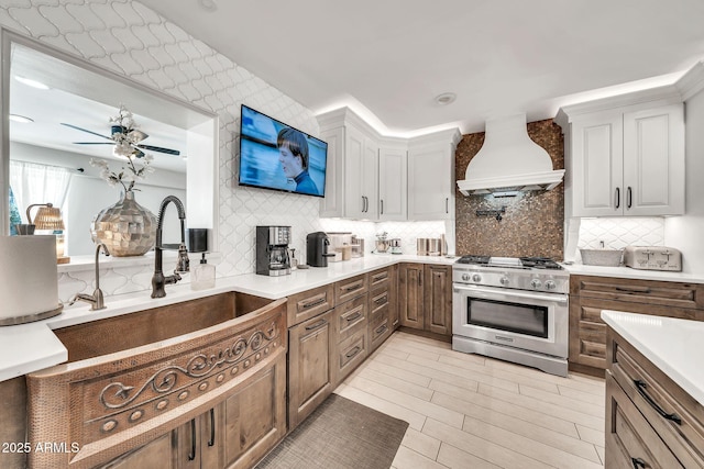 6215 E Surrey Ave, Scottsdale, AZ 85254 - kitchen with high end stove, premium range hood, backsplash, light countertops, and a ceiling fan