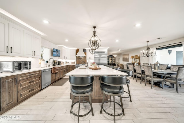 6215 E Surrey Ave, Scottsdale, AZ 85254 - kitchen featuring appliances with stainless steel finishes, a chandelier, premium range hood, decorative backsplash, and recessed lighting