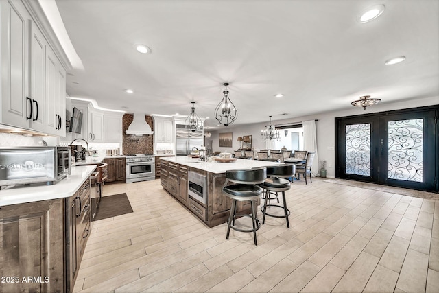 6215 E Surrey Ave, Scottsdale, AZ 85254 - kitchen with appliances with stainless steel finishes, light countertops, a chandelier, a breakfast bar, and decorative backsplash