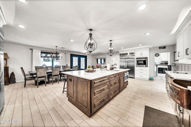6215 E Surrey Ave, Scottsdale, AZ 85254 - kitchen featuring built in appliances, a chandelier, light countertops, white cabinetry, and a center island with sink