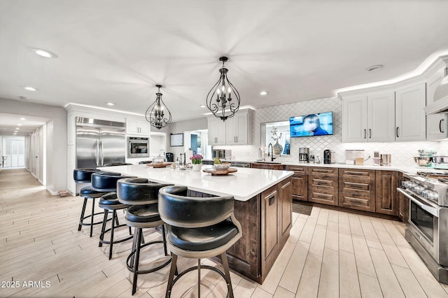 6215 E Surrey Ave, Scottsdale, AZ 85254 - kitchen with high end appliances, a chandelier, light countertops, tasteful backsplash, and light wood finished floors