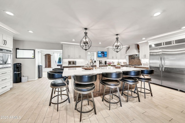 6215 E Surrey Ave, Scottsdale, AZ 85254 - kitchen with appliances with stainless steel finishes, custom exhaust hood, backsplash, recessed lighting, and light wood-style flooring