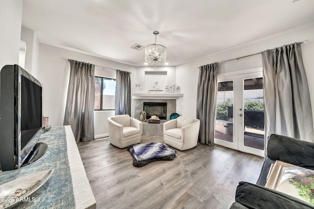 6215 E Surrey Ave, Scottsdale, AZ 85254 - living area with french doors, wood finished floors, a chandelier, and a tiled fireplace