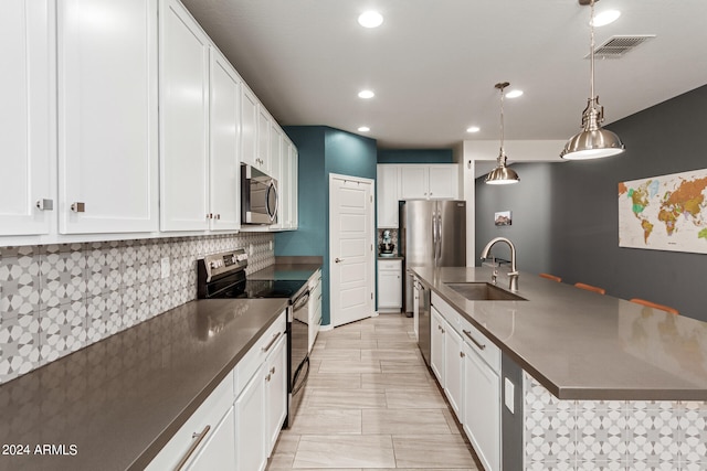 kitchen with hanging light fixtures, appliances with stainless steel finishes, sink, white cabinetry, and decorative backsplash