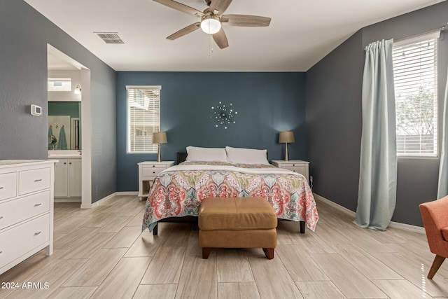 bedroom with ceiling fan, ensuite bathroom, and multiple windows