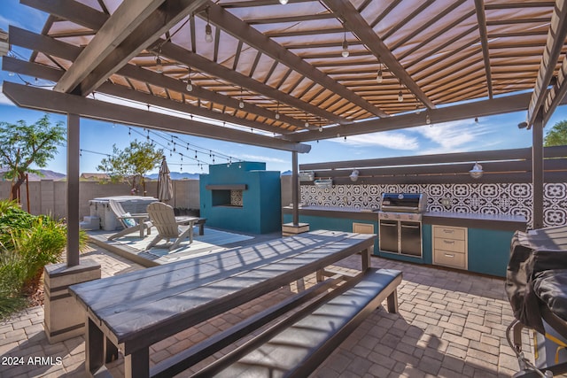 view of patio featuring grilling area, an outdoor fireplace, an outdoor kitchen, and a pergola