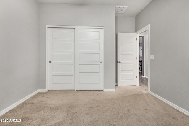 unfurnished bedroom featuring light colored carpet and a closet