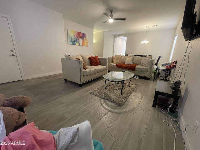 living room with hardwood / wood-style flooring and ceiling fan with notable chandelier