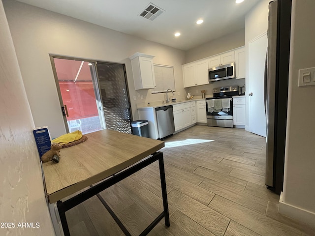 kitchen featuring stainless steel appliances, sink, light hardwood / wood-style floors, and white cabinets