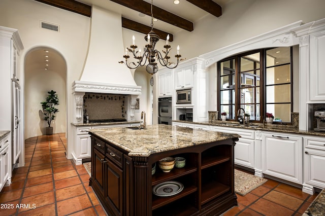 kitchen featuring stainless steel microwave, multiple ovens, visible vents, and white cabinetry