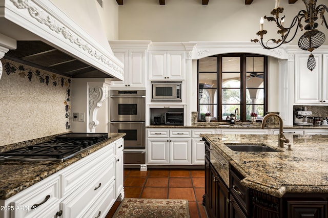 kitchen with stainless steel appliances, tasteful backsplash, white cabinetry, a sink, and premium range hood