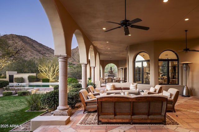 view of patio with ceiling fan, an outdoor living space, and a mountain view