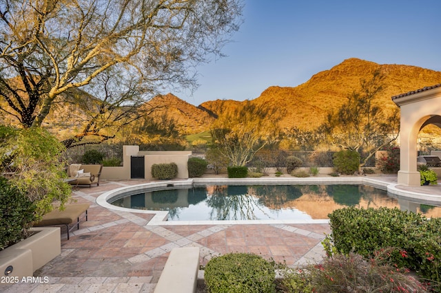 pool featuring a patio, fence, and a mountain view