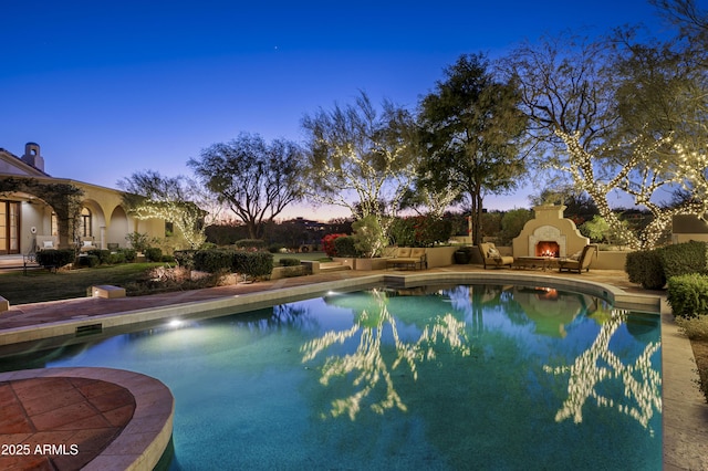 pool with a lit fireplace and a patio