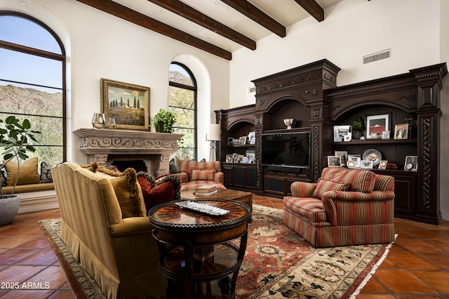 living area with a fireplace, visible vents, a towering ceiling, tile patterned flooring, and beamed ceiling