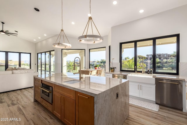 kitchen with white cabinetry, an island with sink, sink, light stone counters, and appliances with stainless steel finishes