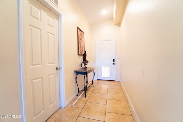 corridor with vaulted ceiling and light tile patterned flooring