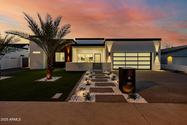 modern home with a garage, concrete driveway, a front lawn, and stucco siding