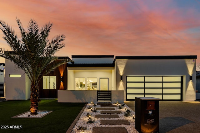 modern home with driveway, an attached garage, and stucco siding