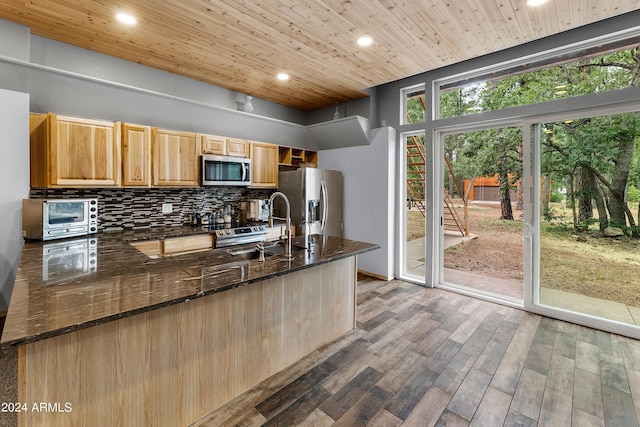 kitchen featuring appliances with stainless steel finishes, sink, backsplash, dark stone counters, and wood ceiling