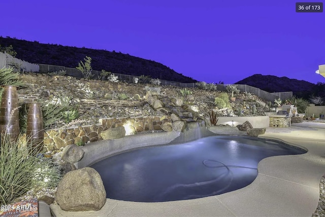 pool at dusk featuring a mountain view, a patio, and a hot tub