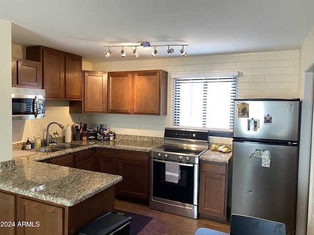 kitchen featuring sink, dark hardwood / wood-style flooring, light stone counters, kitchen peninsula, and stainless steel appliances