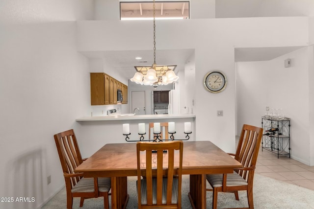 dining space with light tile patterned floors, baseboards, a towering ceiling, and light colored carpet