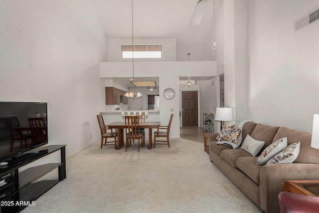 living room featuring light carpet, a high ceiling, and visible vents