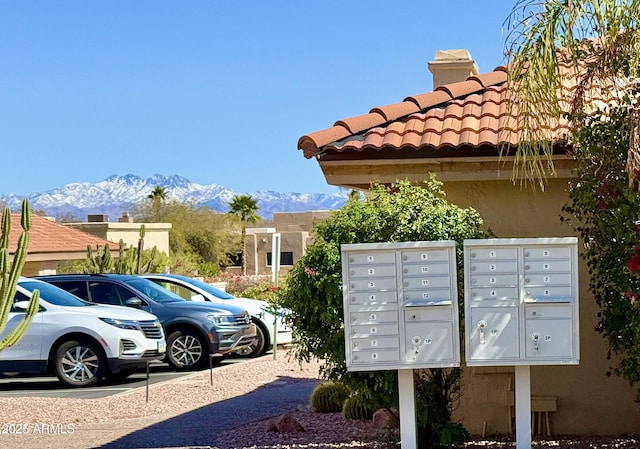 surrounding community with a mountain view, uncovered parking, and mail area