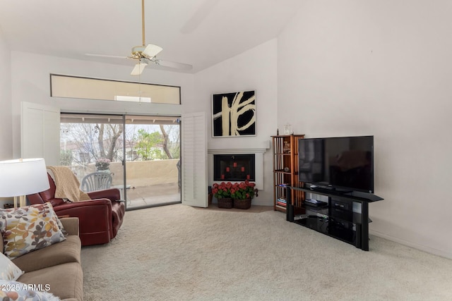 carpeted living area with a fireplace, high vaulted ceiling, and a ceiling fan