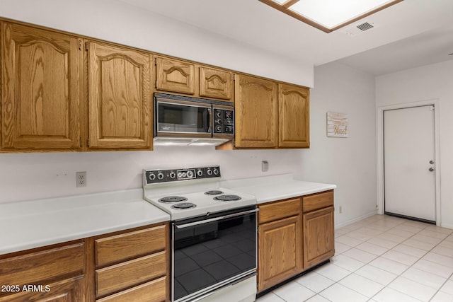 kitchen with brown cabinets, white electric range oven, light countertops, visible vents, and light tile patterned flooring