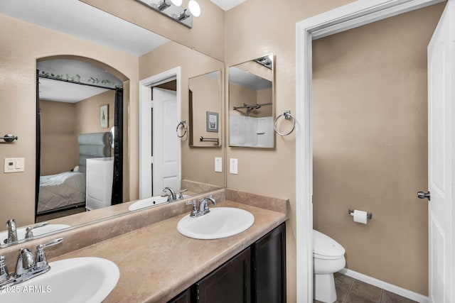 7718 W Pipestone Pl, Phoenix, AZ 85035 - ensuite bathroom featuring double vanity, toilet, tile patterned floors, and baseboards