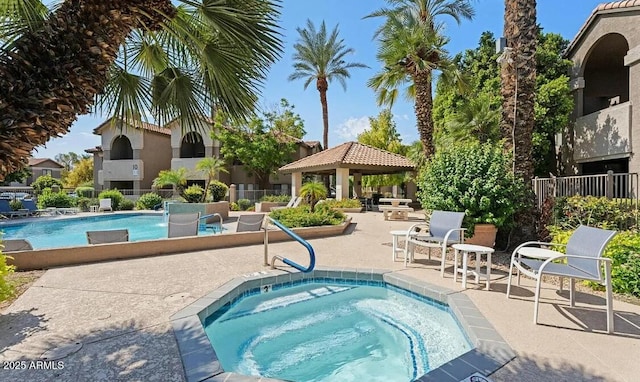 community pool with a community hot tub, a gazebo, a patio area, and fence