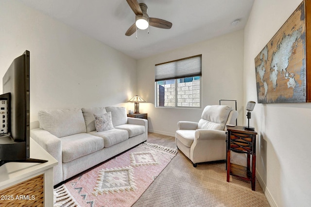 living area featuring carpet flooring, baseboards, and a ceiling fan