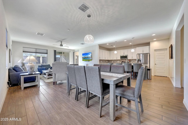 dining area with visible vents, ceiling fan, and wood tiled floor