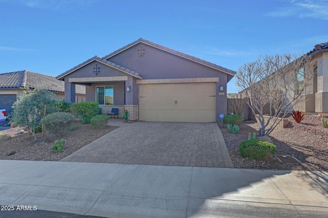 view of front of property featuring stucco siding, decorative driveway, fence, a garage, and a tiled roof