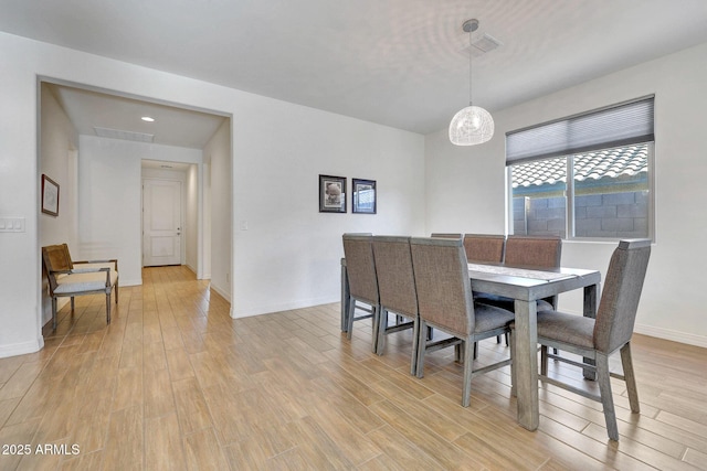 dining space with a chandelier, baseboards, visible vents, and light wood-style flooring