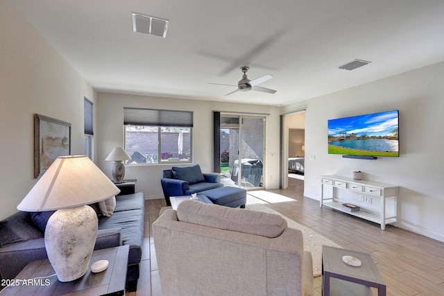 living area featuring ceiling fan, visible vents, baseboards, and light wood-style flooring