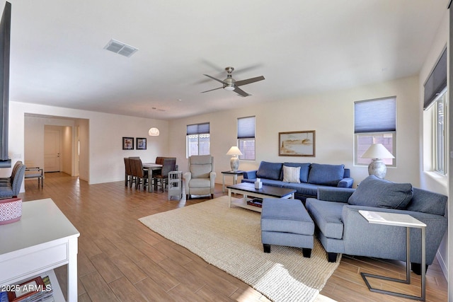 living area with visible vents, ceiling fan, and wood finished floors