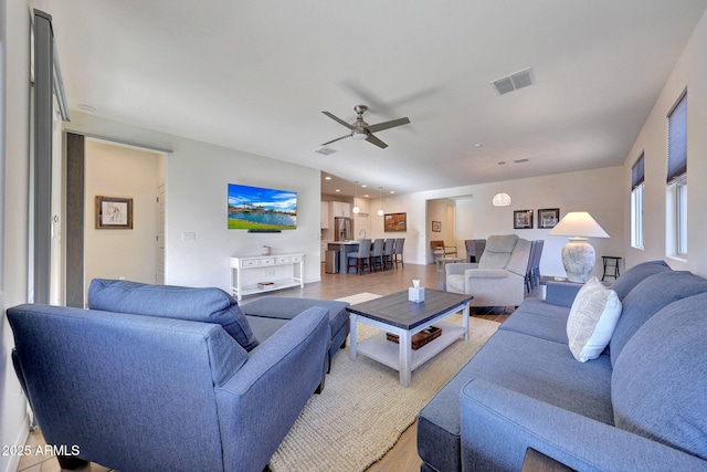 living area featuring visible vents, light wood-style flooring, and ceiling fan