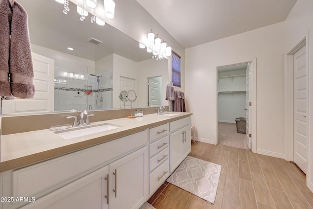 full bathroom featuring a sink, visible vents, double vanity, and a shower stall