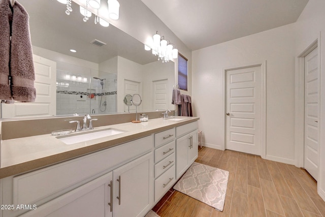 bathroom with wood tiled floor, a stall shower, visible vents, and a sink