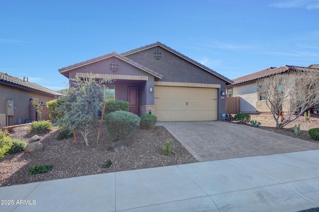 view of front facade with stucco siding, driveway, fence, a garage, and a tiled roof